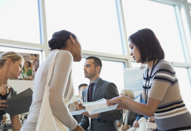 This image depicts two women discussing a registration form that one of the women is holding and showing to the other.