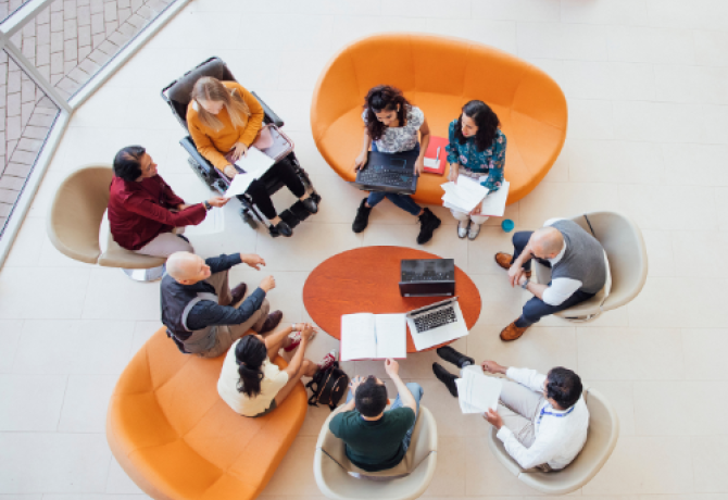 A group of diverse individuals gather in a circle. They are engaged in discussion.